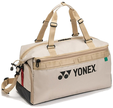 The Yonex BA72611EX Gearlogic Badminton Boston Bag in beige is made from recycled polyester, with tan handles, a front zip pocket, black base, red and black side accents, and the Yonex logo printed in black on the side.