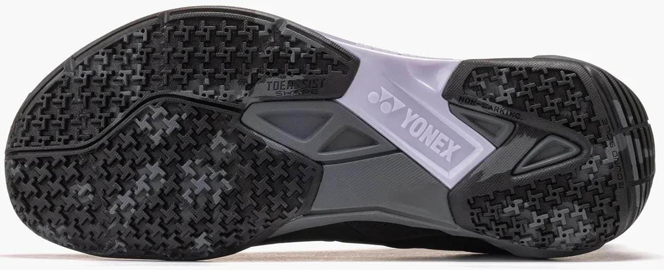Close-up of the sole of Yonex Power Cushion Cascade Drive 3 Unisex Badminton Shoes in black/grey, featuring a textured grip pattern, Yonex logo, and "TOE ASSIST SHAPE" and "NON MARKING" markings.