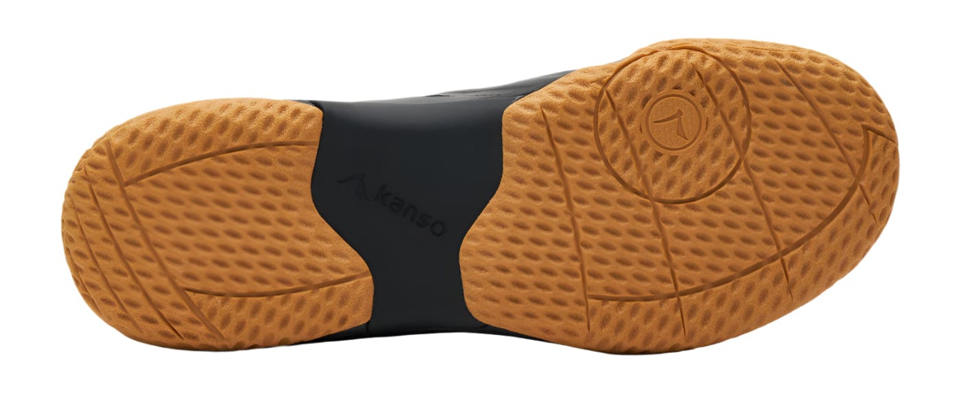 The image displays the sole of the Kanso Equilibrium EQx3 unisex badminton shoe in black, featuring a textured rubber material with a waffle-like tread for grip. Enhanced with Speedlight foam, the light brown sole showcases a "Kanso EQX3" label at its center.