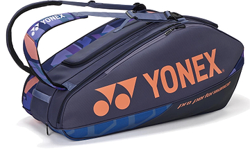 The Yonex 92429EX 9 Racket Pro Badminton Bag in Midnight Navy features purple and orange accents, the Yonex logo, "pro performance" text, Thermo Guard lining, a handle, and adjustable shoulder strap—ideal for pro players.