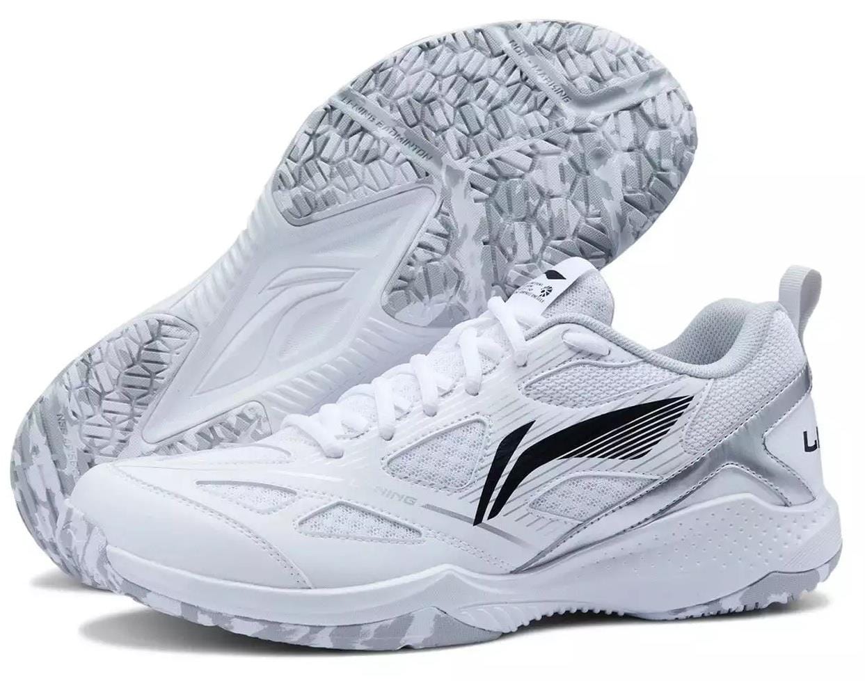 The Li-Ning Blast JF-01 Lite Unisex Badminton Shoes in white feature mesh panels, black side accents, and a high-traction outsole. One shoe is upright while the other displays its sole.