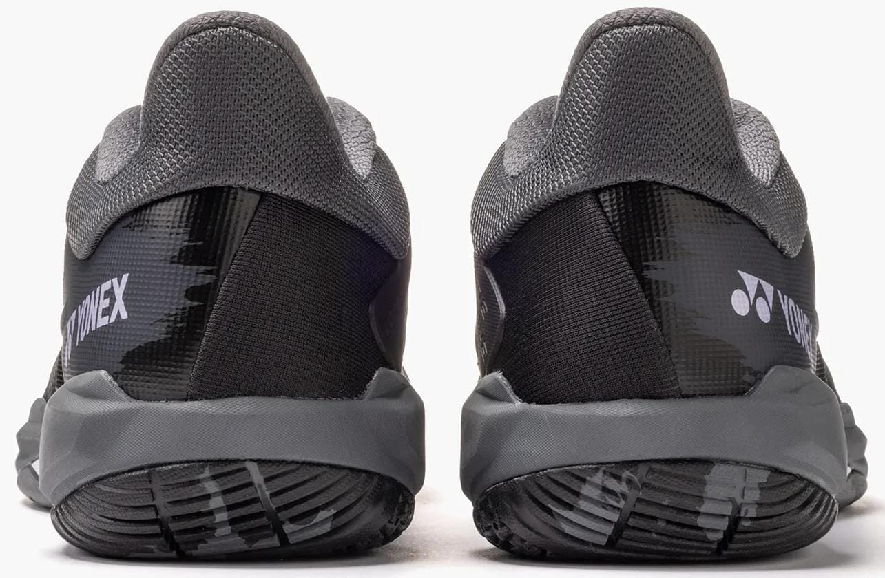 The Yonex Power Cushion Cascade Drive 3 Unisex Badminton Shoes in black and grey feature textured soles and the Yonex logo on the heels, offering comfort and performance—ideal for badminton enthusiasts.