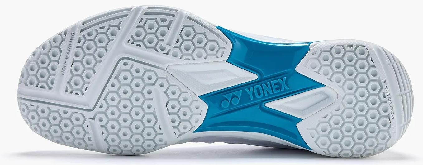 The Yonex Power Cushion Aerus X2 Unisex Badminton Shoes in White/Blue feature a white sole with hexagonal tread, blue accents, the Yonex logo, and "NON-MARKING" plus "ROUND SOLE" printed—ideal for lightweight indoor court play.