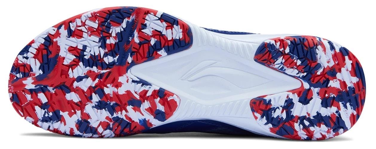 The image displays the sole of the Li-Ning Blast JF-01 Lite Unisex Badminton Shoes in blue and red, featuring a textured pattern, lightweight build, rubber-like segments, and a central wavy line.