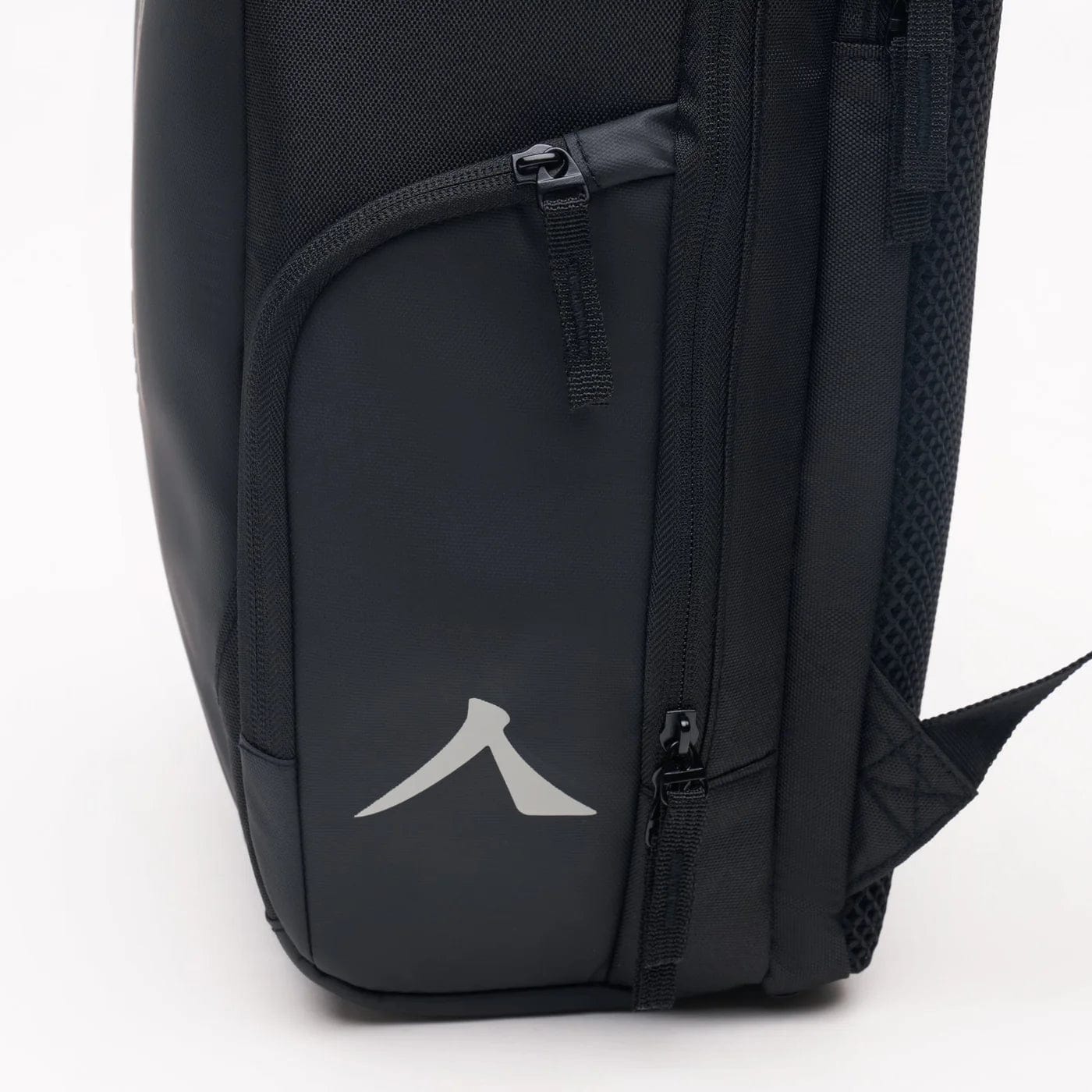 Close-up of a black Kanso Intuko Badminton 23L Backpack showing two zippered compartments. The lower one has a reflective arrow logo. With visible stitching and textured side panels, this durable companion by Kanso is ideal for any adventure.
