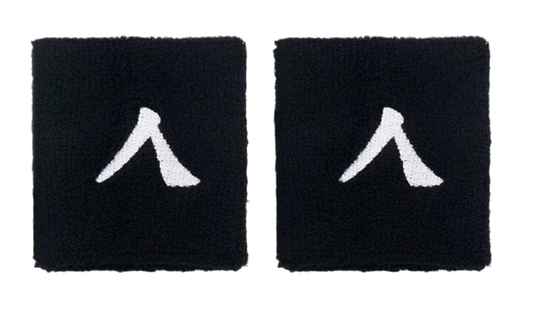The Kanso 7cm Wristband - 2 Pack offers two black wristbands with a white abstract symbol resembling a stylized letter, crafted from absorbent fabric for maximum comfort, elegantly highlighted on a simple white backdrop.