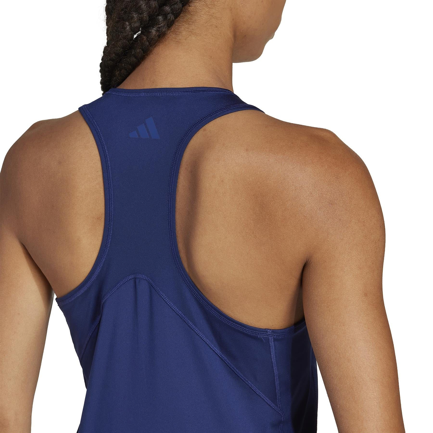 The image shows a person with braided hair wearing a navy adidas Women's Club Badminton Tank Top featuring a racerback and center Adidas logo. Made from recycled materials, it's ideal for staying cool and stylish on the court.