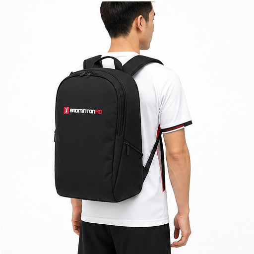 A person in a white sports shirt and black shorts stands facing away, carrying the BadmintonHQ Badminton Backpack - Black with the BadmintonHQ logo visible on the back.