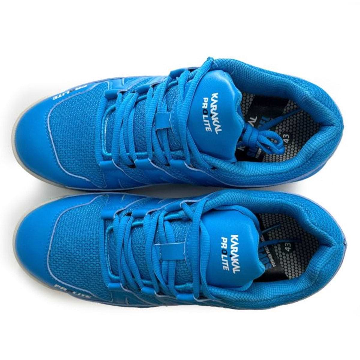 A pair of vibrant blue Karakal sneakers is shown from above. The Karakal KF Pro Lite Badminton Shoes include laces and a mesh-like texture, offering lateral stability. With the insoles slightly visible, they feature shock-absorbing gel insoles for enhanced comfort.