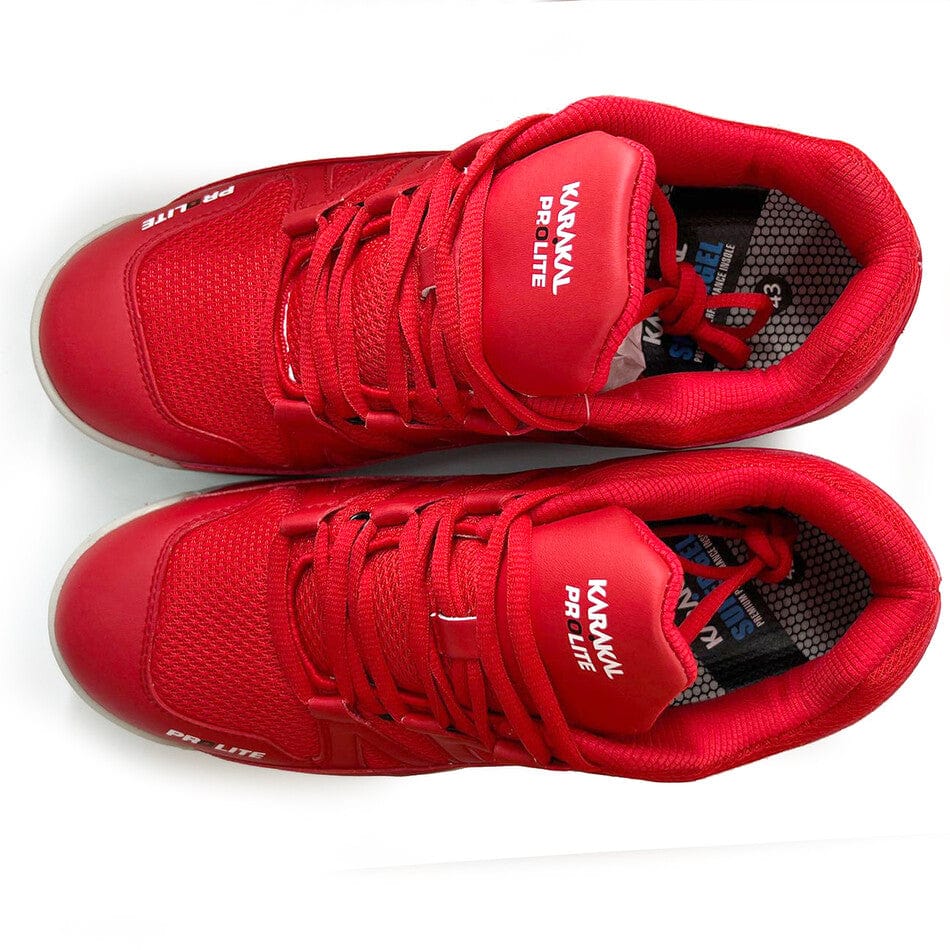 A pair of vibrant new red sneakers with white accents, featuring the brand name "Karakal" prominently on the tongue and side. Emphasizing their lateral stability, these Karakal KF Pro Lite Badminton Shoes also include a shock-absorbing gel insole for enhanced comfort. Ideal for those looking for both style and support.