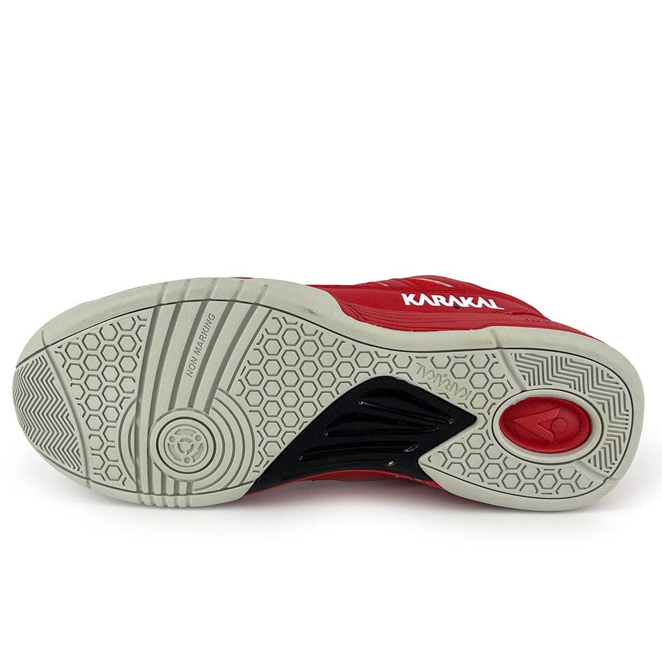 A view from underneath the Karakal KF Pro Lite Badminton Shoes - New Red reveals a white sole with a honeycomb grip pattern. The shoe provides lateral stability, features a circular grip design at the toe, includes black arch support and a red heel cushion, and comes with shock-absorbing Gel Insole. The brand name is displayed on the side.