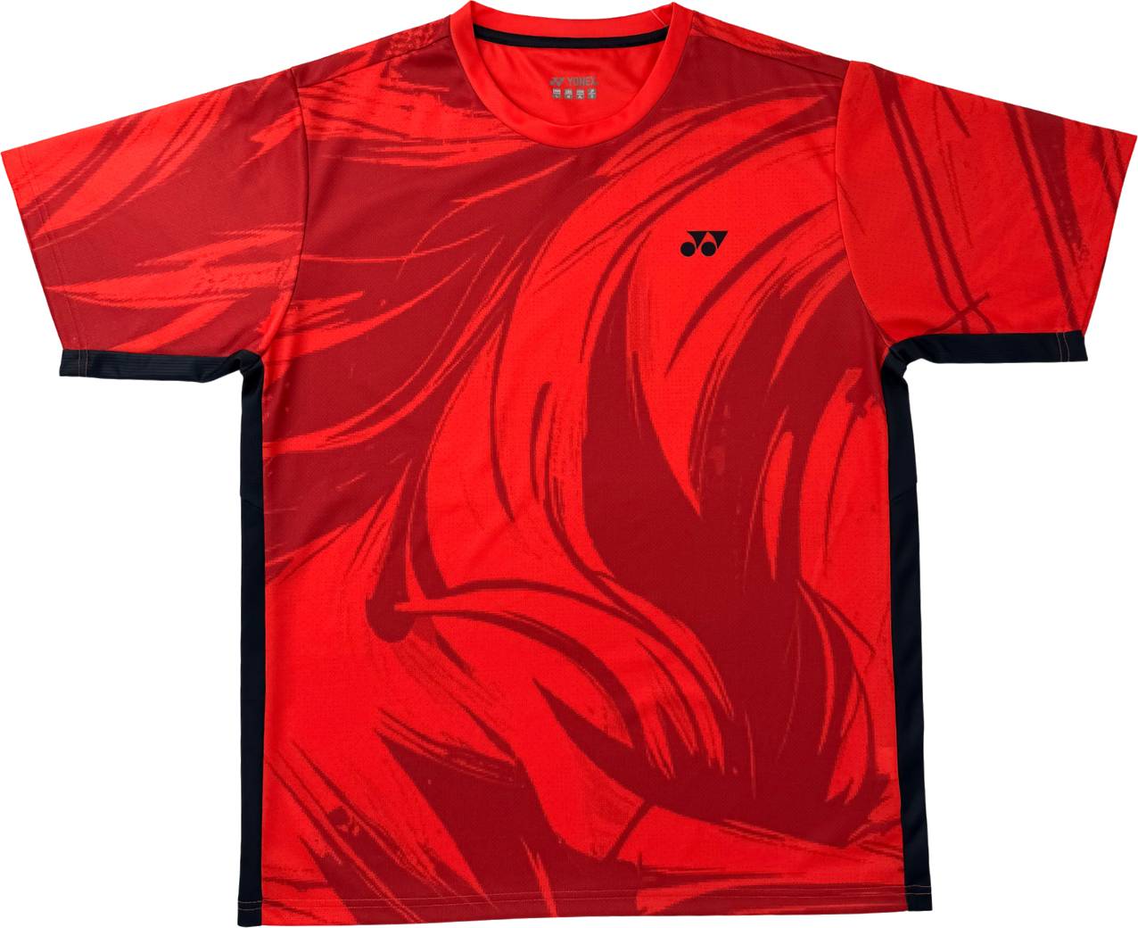 The Yonex YTM14 Men’s Badminton T-Shirt in Coral is a short sleeve sports tee featuring bold, abstract dark red patterns and a small black and white Yonex logo on the upper left chest. Black accents run along the sides and sleeve edges, making it an excellent choice for team apparel.