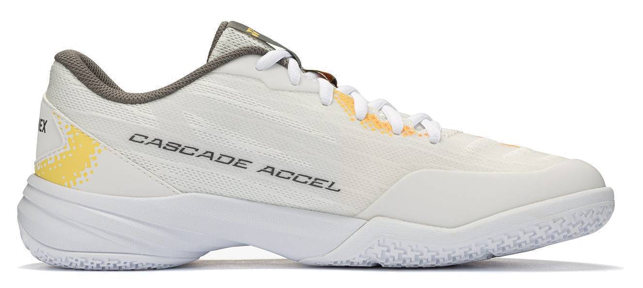 A white Yonex Power Cushion Cascade Accel unisex badminton shoe with gray lining, orange accents, and “CASCADE ACCEL” displayed on the side, shown in a profile view against a plain background. This intermediate model features Yonex Power Cushion technology for enhanced comfort and shock absorption.