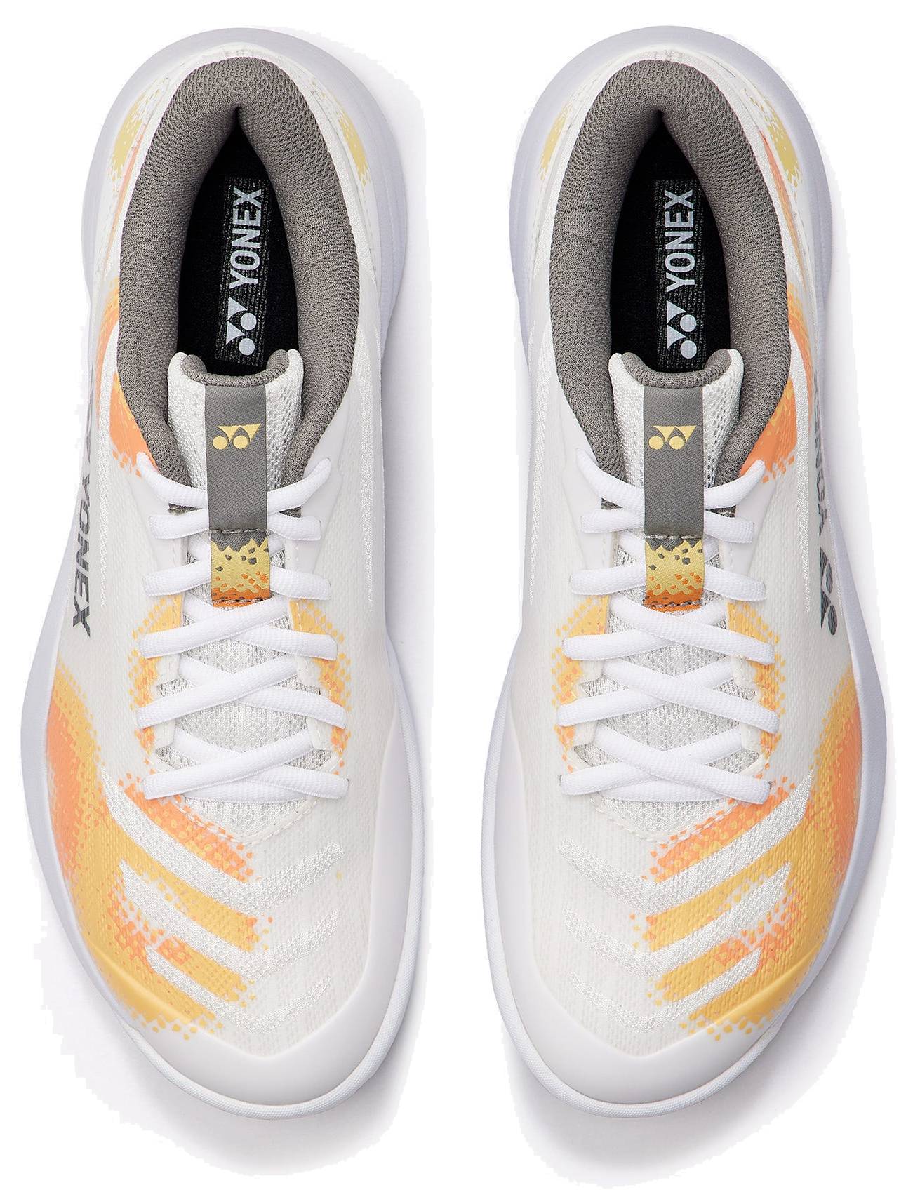 A pair of Yonex Power Cushion Cascade Accel unisex badminton shoes in white and orange, featuring white laces, a white base, and orange and yellow accents. Viewed from above, this intermediate shoe model offers the Yonex Power Cushion for improved comfort and shock absorption, with the Yonex logo displayed on the tongue and inner sole of both shoes.
