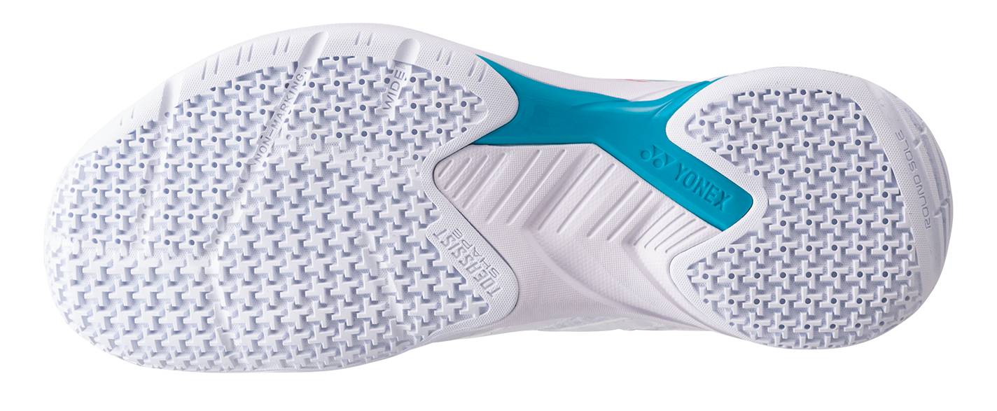 The image displays the white textured sole of the Yonex Power Cushion Cascade Accel Wide Unisex Badminton Shoes in White / Light Blue, showcasing small square grips and a blue accent on the arch area with visible “Yonex” branding. This shoe features Yonex Power Cushion technology for enhanced comfort and stability during play.