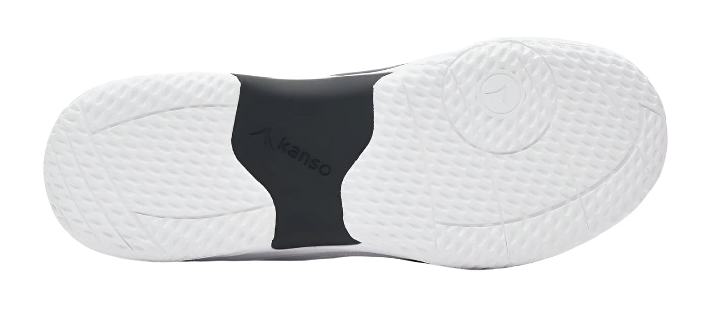 The image depicts the sole of the Kanso Equilibrium EQx3 Unisex Badminton Shoes in white/black with a textured rubber surface. The center features black arch support labeled "Kanso," enhanced with Speedlight Foam for shock absorption, and grip patterns for superior traction.