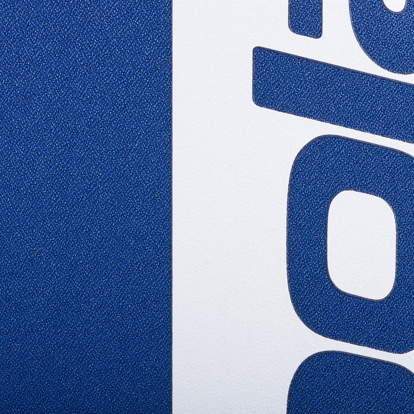 Close-up of the Babolat Court Hero Badminton Backpack - Dark Blue by Babolat, showing its textured recycled PET blue surface beside a white section with bold blue lettering and the curved lower part of a letter "g.