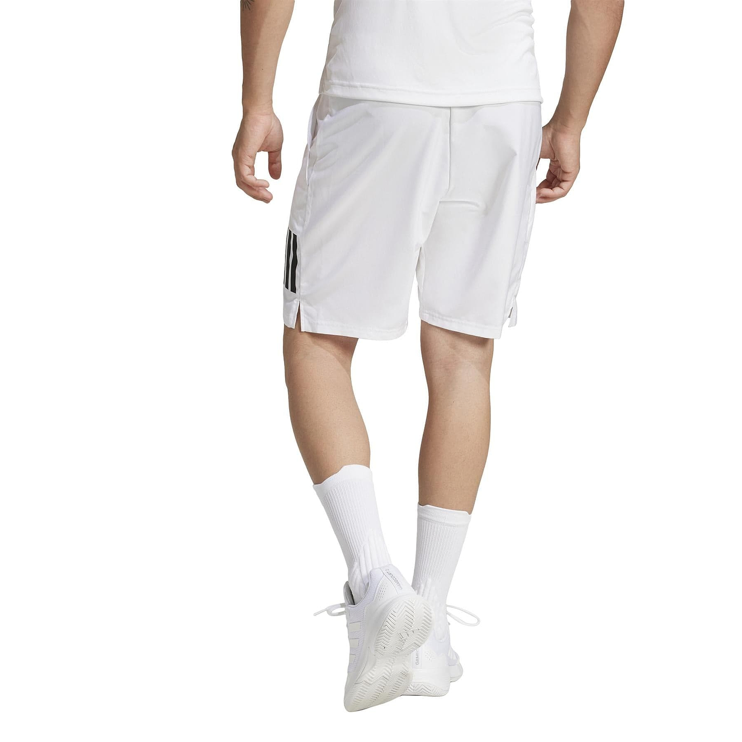 A person in a white athletic outfit walks away from the camera wearing ADIDAS Men's 3 Stripe Badminton Shorts, featuring moisture-wicking recycled materials. They sport white socks and shoes, with part of a black stripe visible on their shorts.