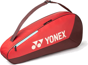 The Yonex 42523EX Team 3 Racket Badminton Bag in Ruby Red is a lightweight, red and brown bag with a shoulder strap, zipper, and white Yonex logo, designed to hold up to 3 rackets for convenient on-the-go use.