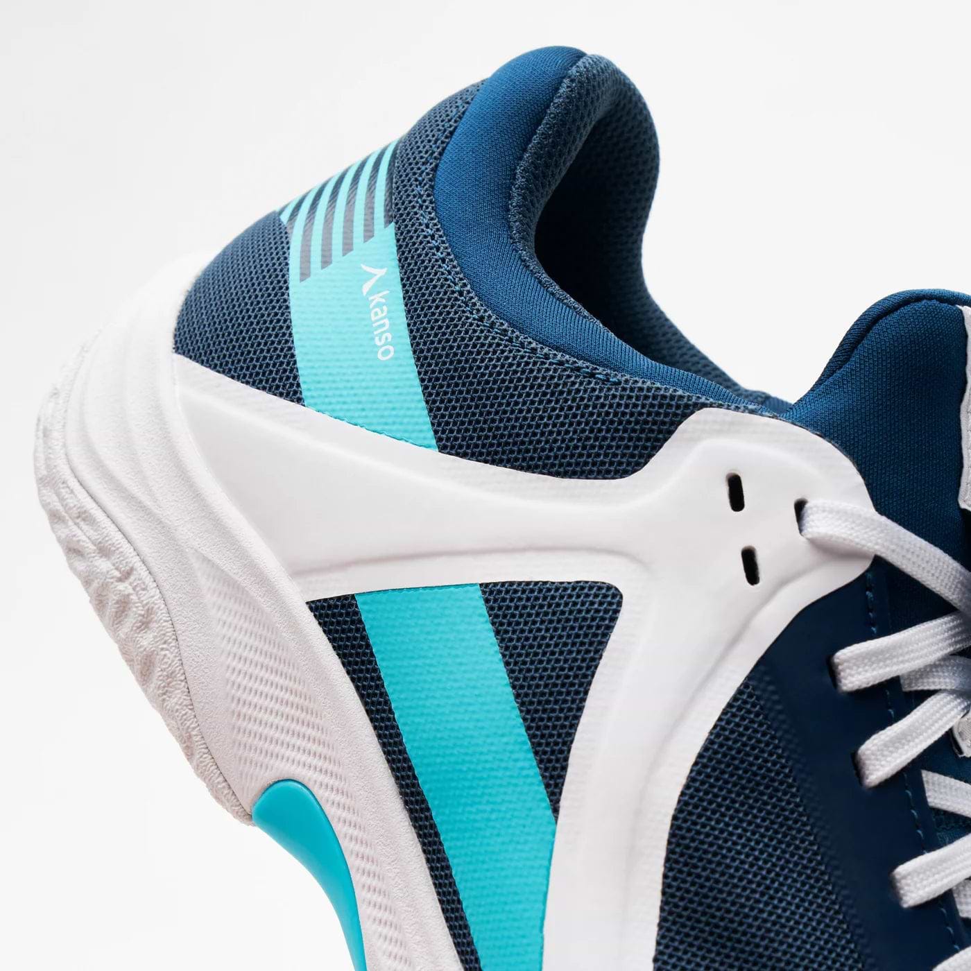 Close-up of the Kanso Equilibrium EQx3 Unisex Badminton Shoes in navy, showcasing teal accents and a textured sole for energy return. The sleek design features mesh material for breathability and a side logo.