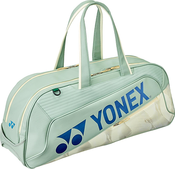 The Yonex 02631WEX Expert Tournament Badminton Bag in smoke green features cream handles and zipper, blue Yonex logo and text, a subtle shuttlecock pattern, and Thermo Guard technology to protect your gear.