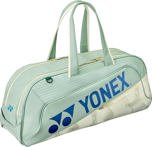 The Yonex 02631WEX Expert Tournament Badminton Bag in smoke green features cream handles and zipper, blue Yonex logo and text, a subtle shuttlecock pattern, and Thermo Guard technology to protect your gear.