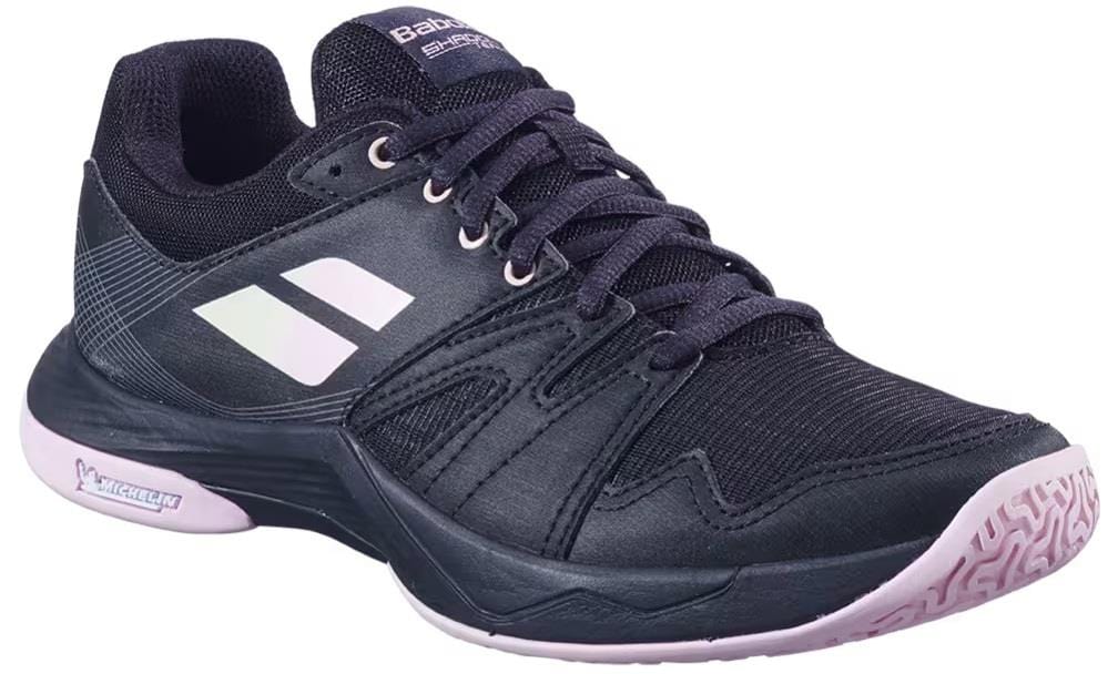 The Babolat Shadow Team 2 Women’s Badminton Shoes in Black/Black feature white accents, a pink and white textured sole, laces, and brand logos on the side and tongue, shown against a white background.