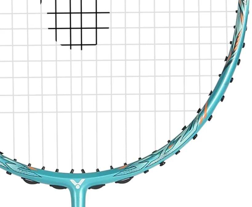 A close-up of the Victor Jetspeed S 12TD R 4U Badminton Racket in green, highlighting its string pattern, part of the Aero-Sword frame by Victor, black grommets, and unique patterned detailing.