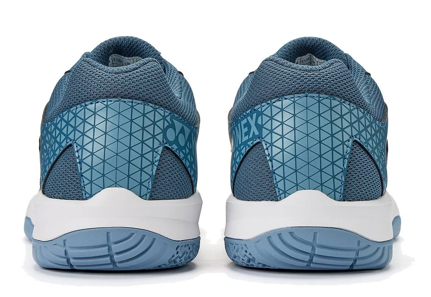 The Yonex Power Cushion Strider Ray Unisex Badminton Shoes in teal blue feature a geometric heel pattern, mesh fabric, and white soles with blue treads for superior shock absorption, inspired by the Yonex Power Cushion design.