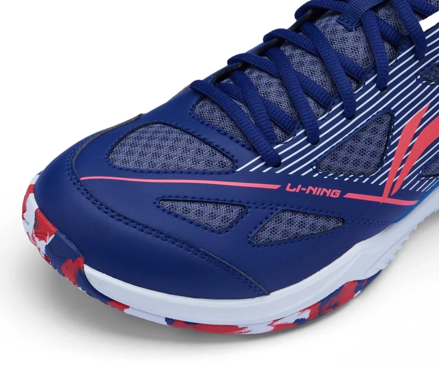 Close-up of the Li-Ning Blast JF-01 Lite Unisex Badminton Shoes in Blue/Red, featuring navy blue laces, mesh panels, and "LI-NING" branding. Lightweight build and red, white, and blue sole deliver style and performance.