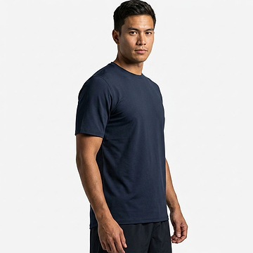 A man with short dark hair wears a plain HEAD Simple Mens Badminton T-Shirt in navy and dark shorts, standing slightly to the side against a white background.