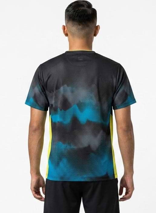 A man with short dark hair is seen from behind, wearing a Yonex YTM2025A Mens Badminton T-Shirt in black with a pixelated pattern and yellow side panels, plus black shorts, standing against a plain white background.
