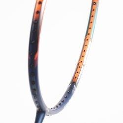 Close-up of a badminton racket head, showcasing the ultra-lightweight Li-Ning Windstorm 72 6U design. The orange and black color scheme accentuates the strings and frame against a white background.