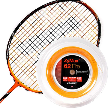 An orange and black badminton racket rests beside a spool of Ashaway Zymax 62 Fire Badminton String, which is perfect for professional players seeking maximum repulsion. The vibrant orange string is highlighted within its transparent packaging, featuring a striking black and red label from the Ashaway brand.