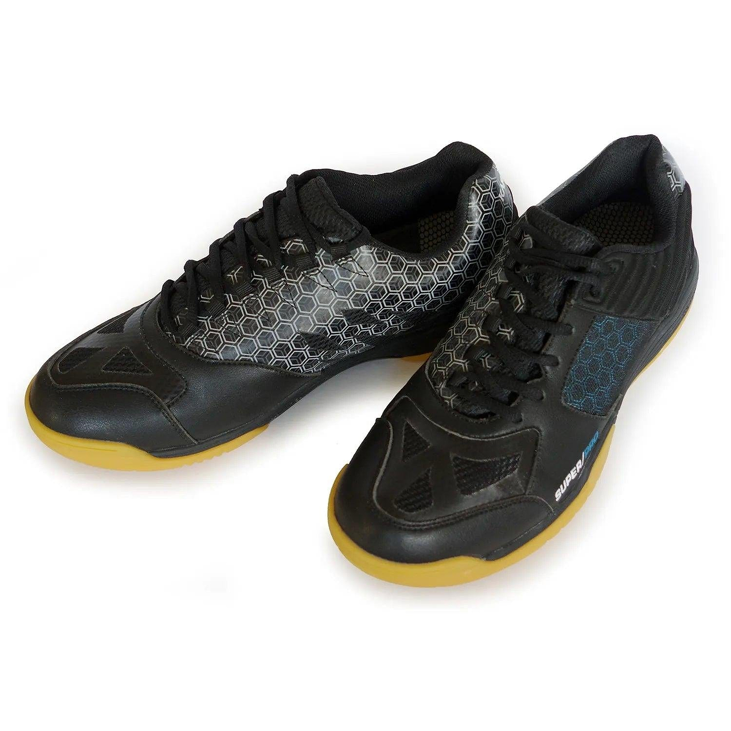 The Karakal Super Pro Indoor Court Badminton Shoes feature a sleek black design with honeycomb-patterned accents and gum rubber soles, viewed from a 3/4 angle. The left shoe showcases a distinctive gray pattern, while the right shoe is adorned with a blue detail on the side, complemented by an asymmetric lace system for an enhanced fit.