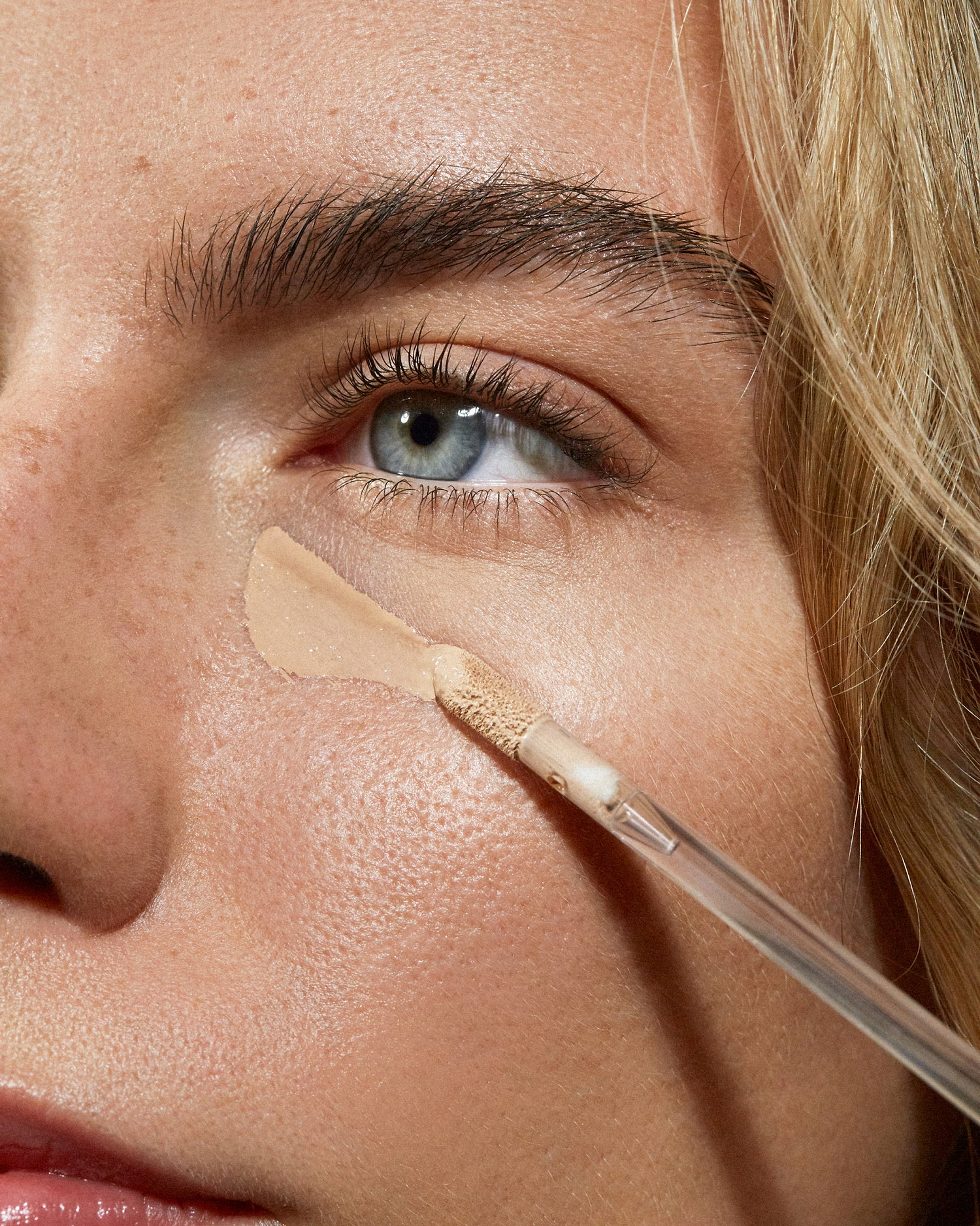 Model wearing MÁDARA Organic Skincare the concealer sand on A6109 concealer on skin; close-up portrait shows natural application results.
