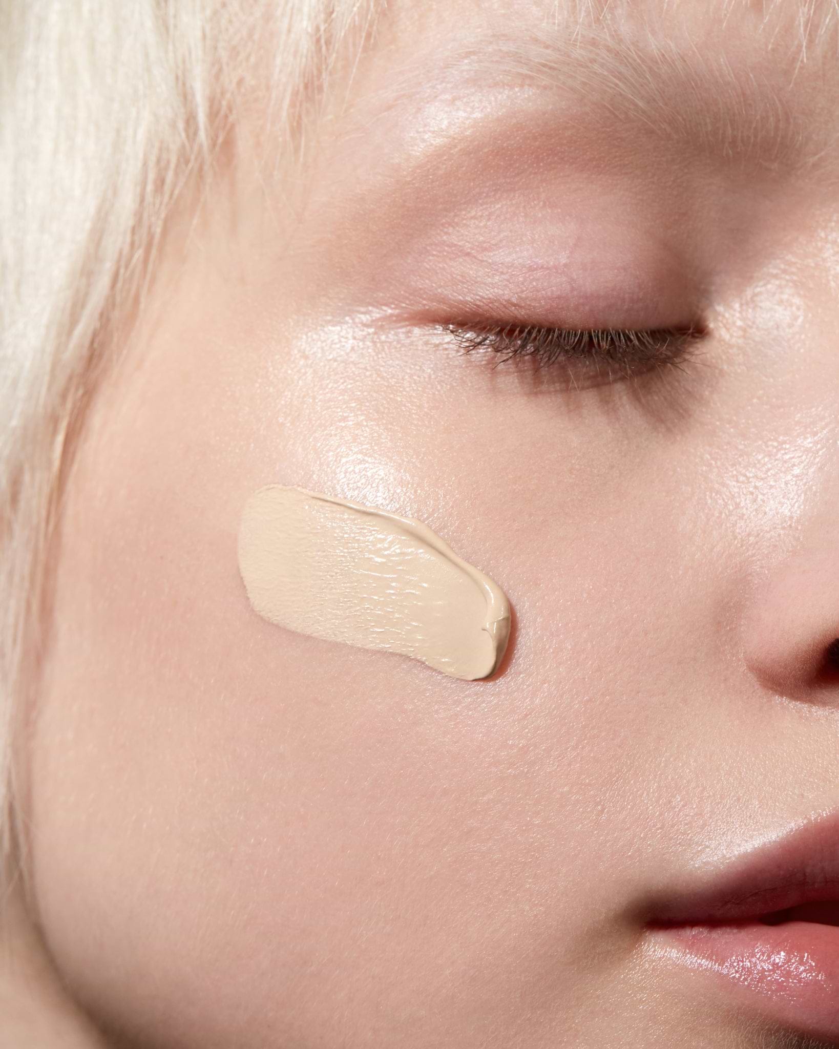Model wearing MÁDARA Organic Skincare skinonym porcelain on A6081 on skin; close-up portrait shows natural application results.