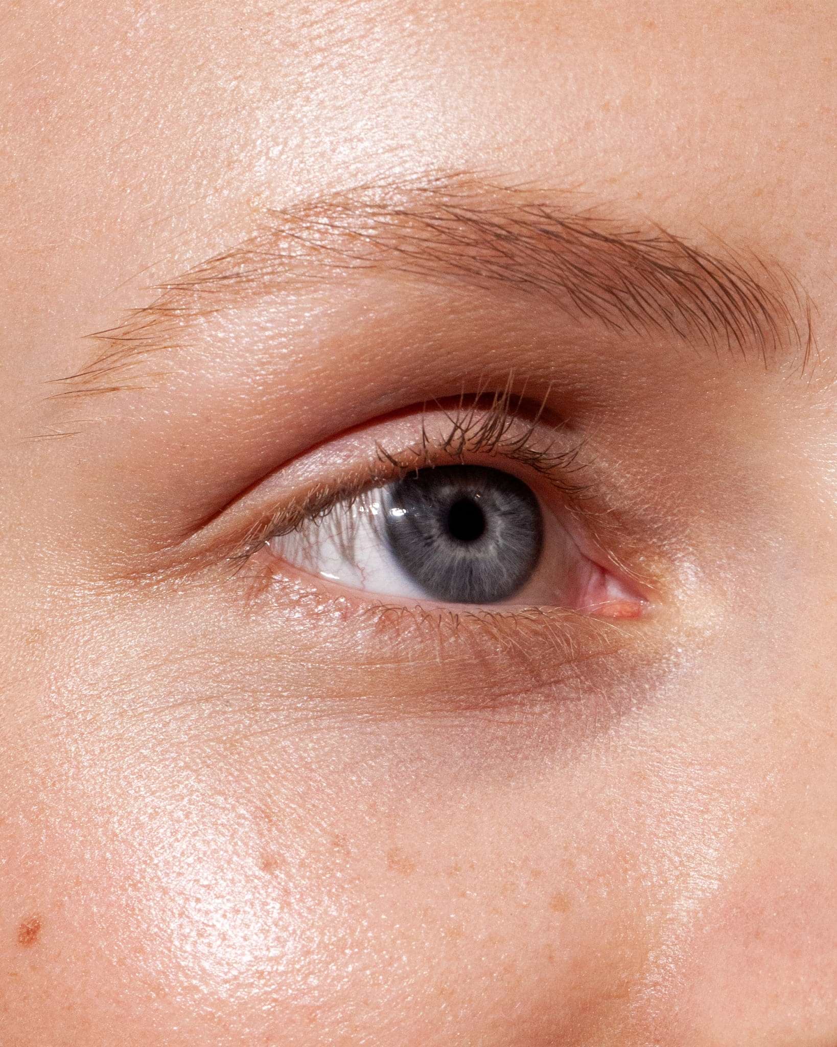Model wearing MÁDARA Organic Skincare brow and lash booster smoky blonde on A6702 on skin; close-up portrait shows natural application results.