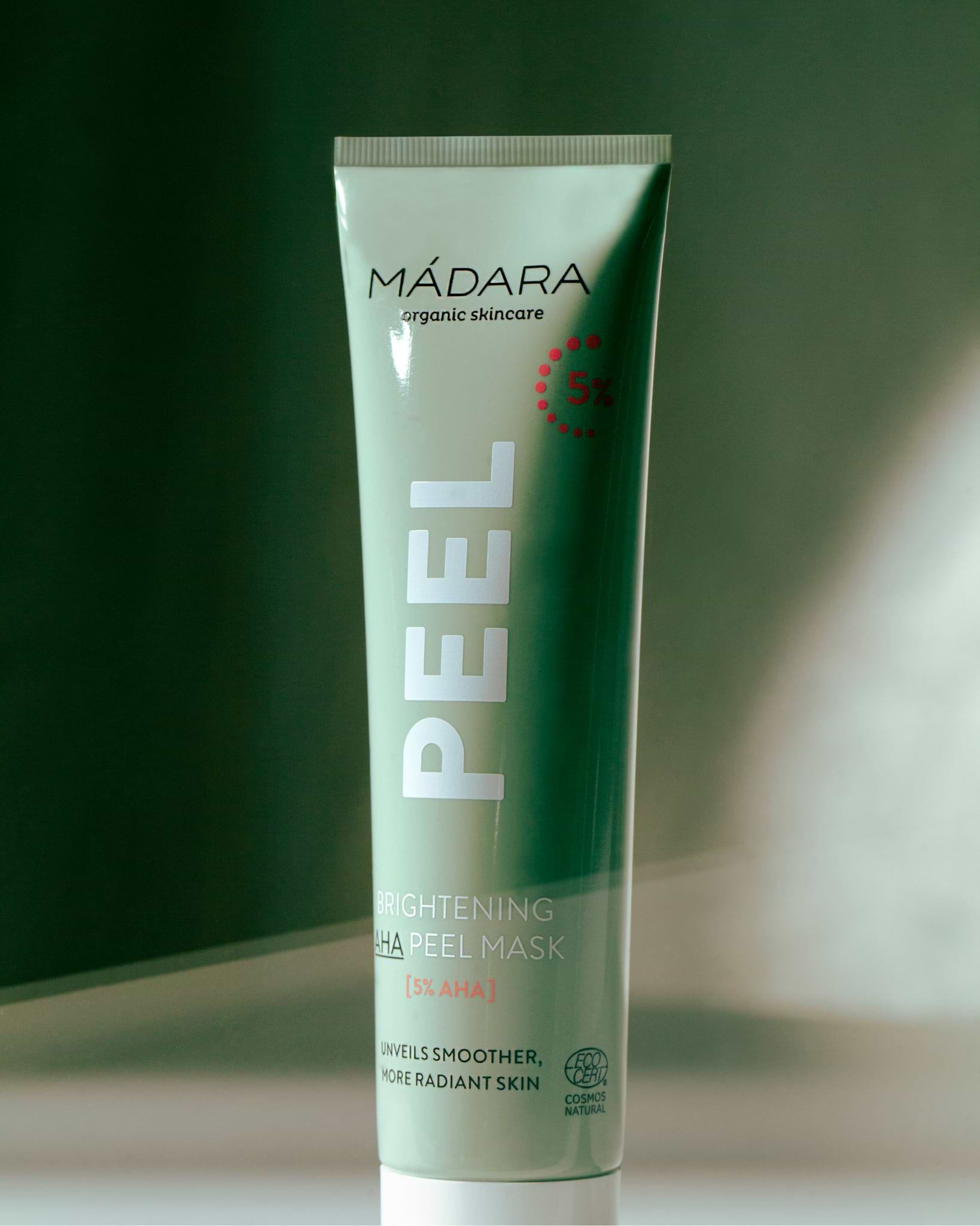 Model wearing MÁDARA Organic Skincare peel face mask A2101 face mask on skin; close-up portrait shows natural application results.