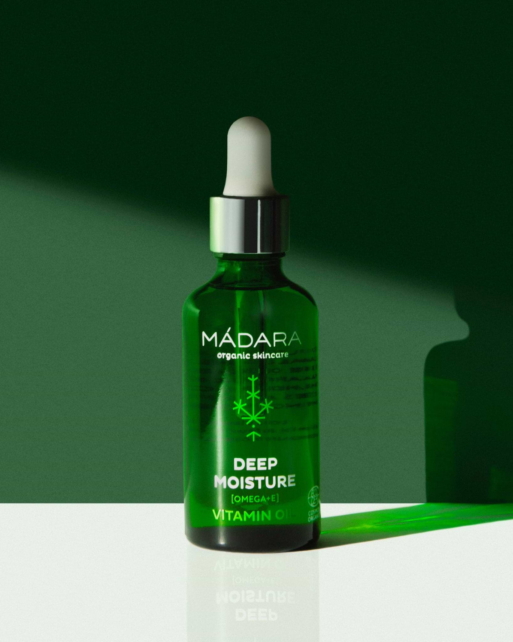Model wearing MÁDARA Organic Skincare omega and vitamin e oil for face A2281 face oil on skin; close-up portrait shows natural application results.