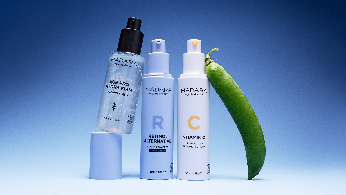 MÁDARA Age Pro Hydra Firm jelly, Retinol Alternative night cream and Vitamin C cream displayed on a blue background with a green pea pod