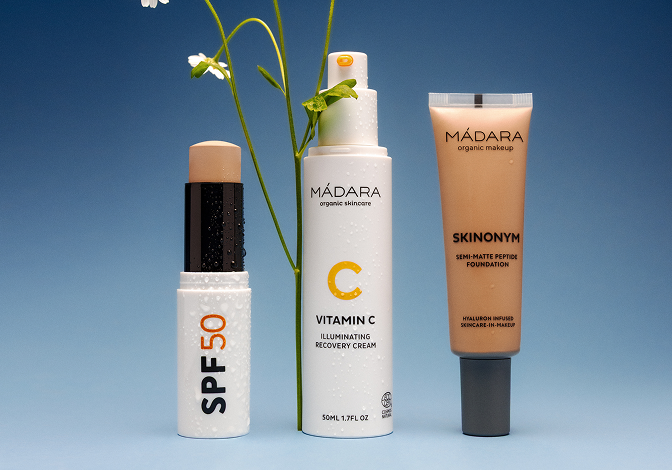 MÁDARA SPF50 stick, Vitamin C cream and Skinonym foundation displayed on a blue background with wildflowers