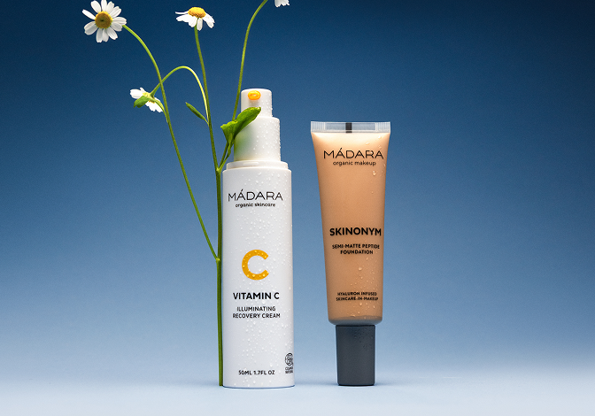MÁDARA Vitamin C cream and Skinonym foundation displayed on a blue background with white wildflowers