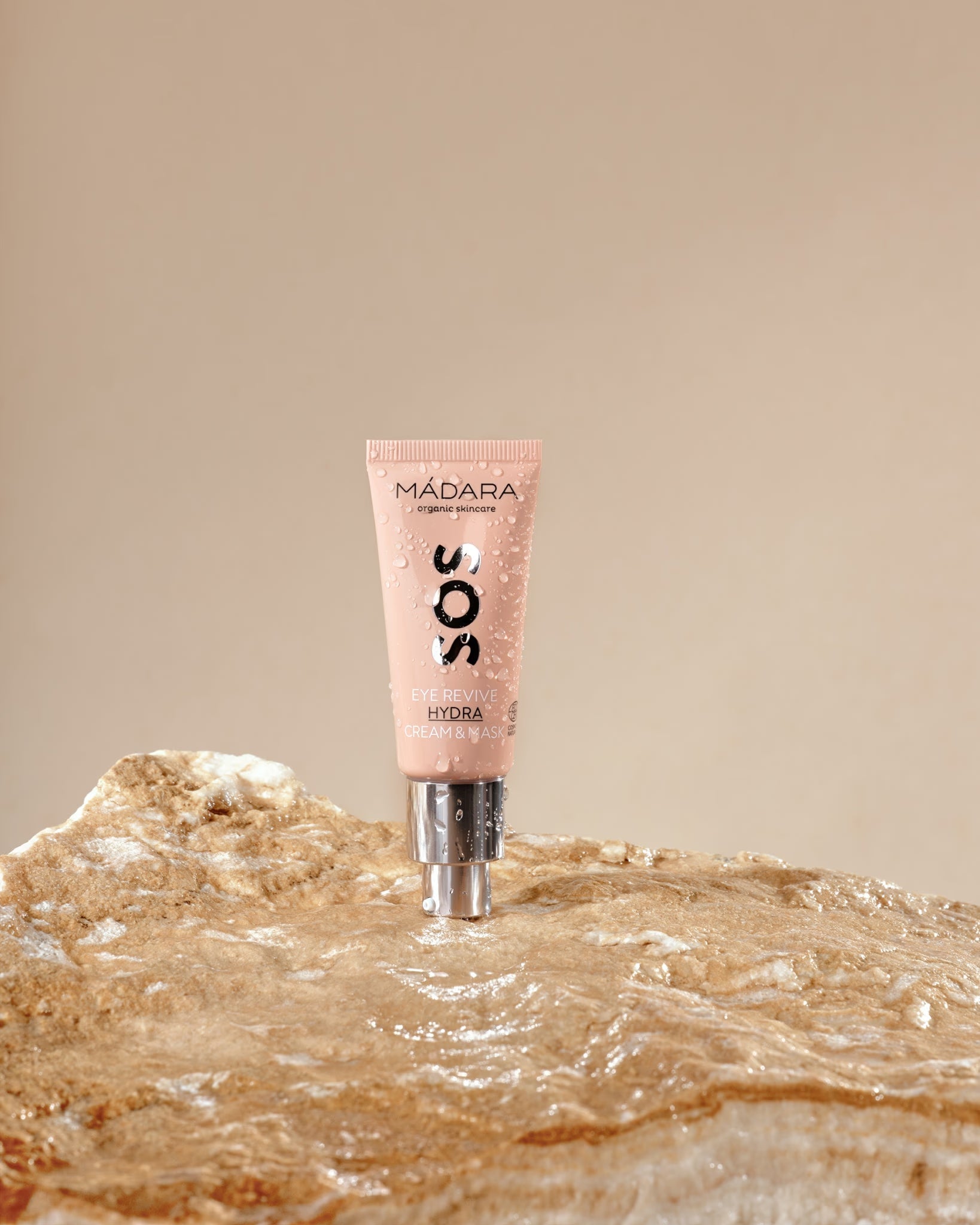 MÁDARA SOS Eye Cream Mask tube resting on a wet rock.