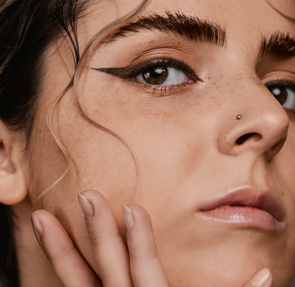 close-up of womans facial skin and her eyebrows covered with Madara Grow Fix Tinted lash booster