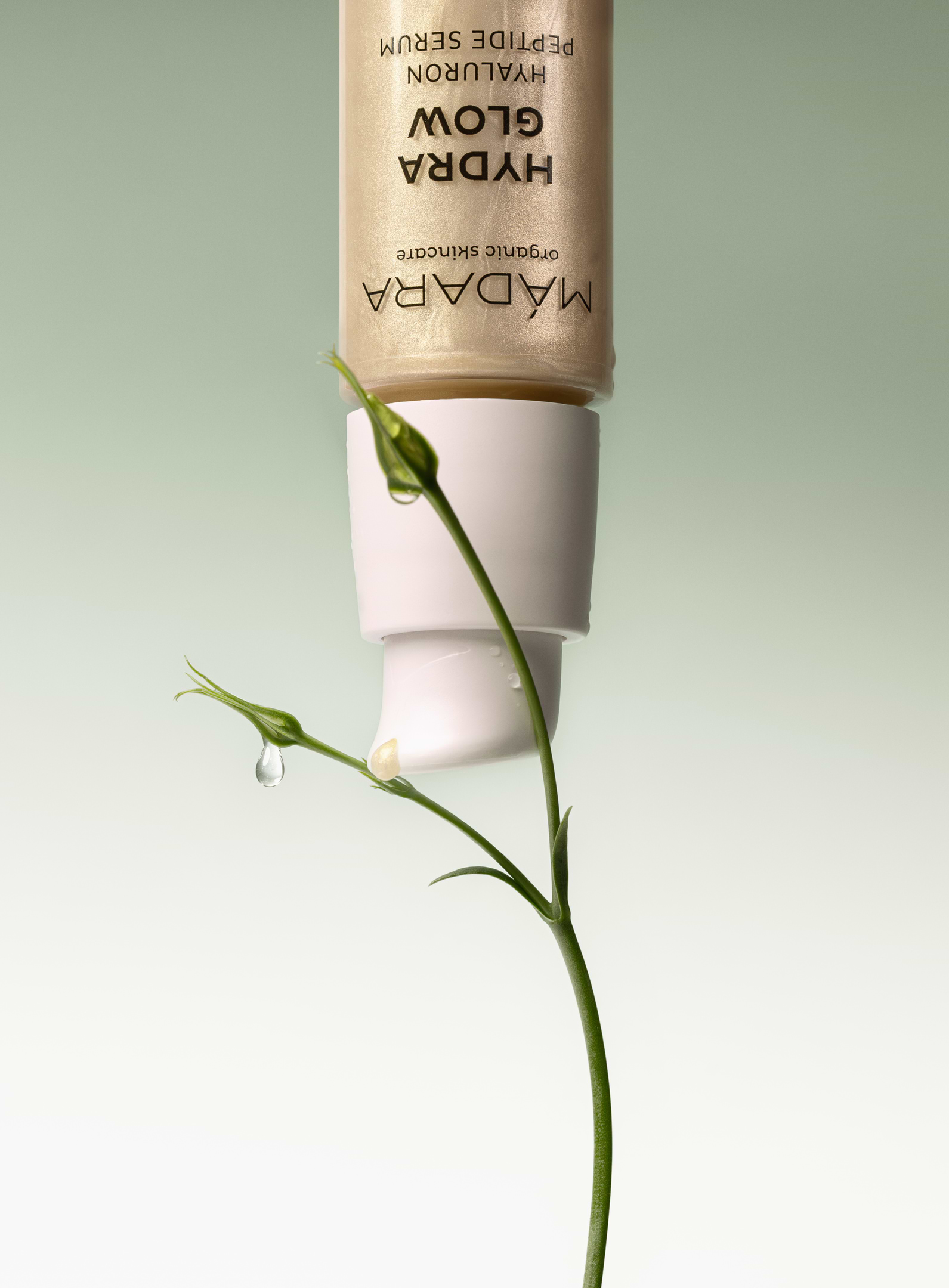 MÁDARA Hydra Glow Hyaluron Peptide Serum with golden formula and natural plant detail, highlighting hydration and radiance in organic skincare