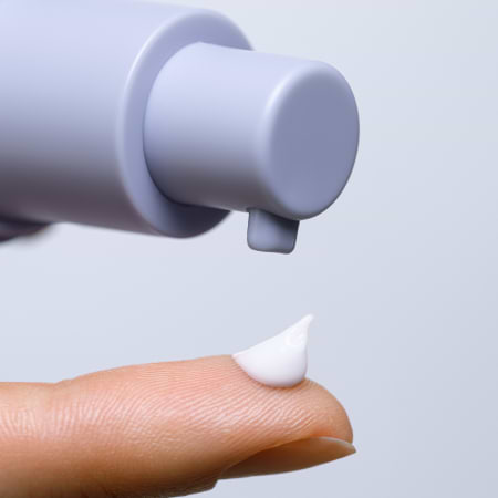 A finger catching a drop of white cream dispensed from Retinol Alternative serum.