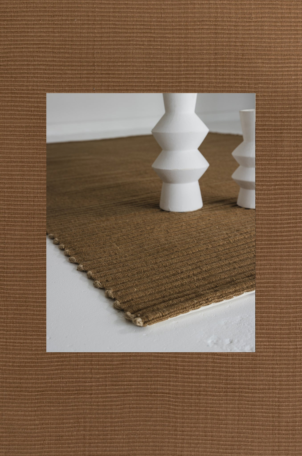 Brown textured rug with white geometric candle holders on a white surface
