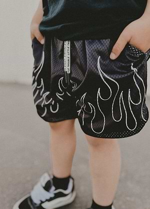 Kid wearing Little Trouble Heater Flame Shorts Black on a neutral background