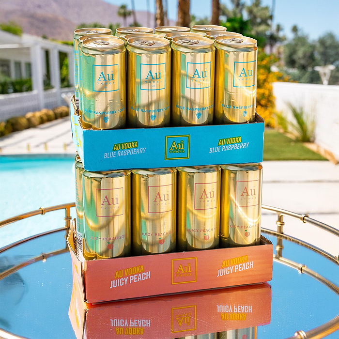 Au Vodka Blue Raspberry and Juicy Peach cans stacked on a mirrored tray outdoors